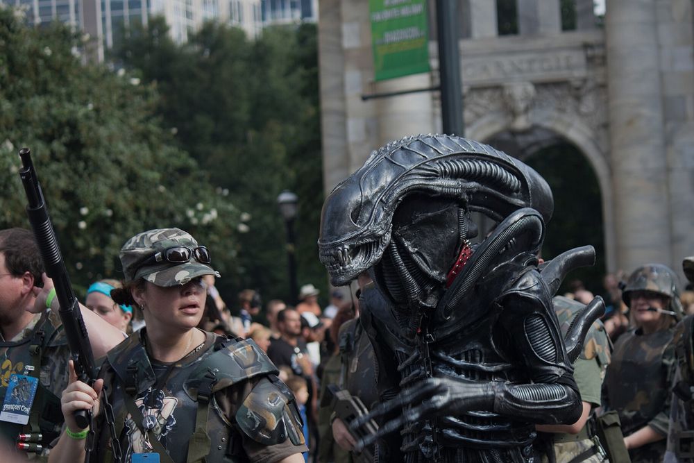 Nachgebautes Xenomorph-Kostüm neben Besuchern in Colonial-Marine-Montur bei einer Parade