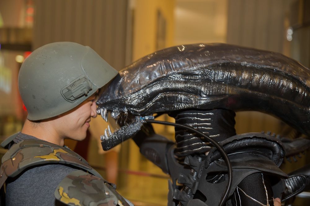 Ein detailgetreues, selbst gebautes Xenomorph-Kostüm neben einem als Colonial Marine verkleideten Besucher