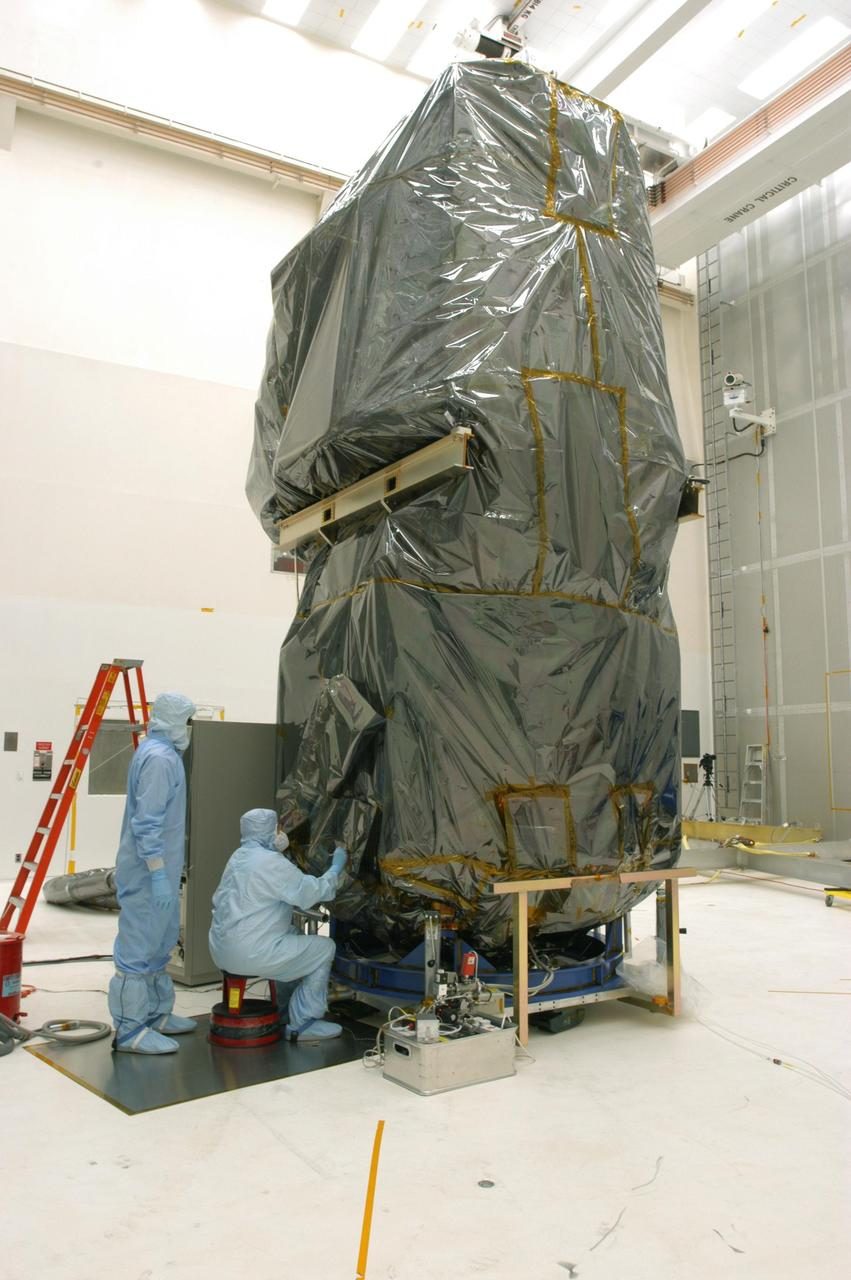 Techniker heben im Reinraum die Schutzhülle vom Swift-Satelliten