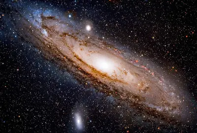 Die Andromedagalaxie (M31), eine ausgedehnte Spiralgalaxie mit hellem Kern und blau leuchtenden Spiralarmen vor einem sternreichen Hintergrund