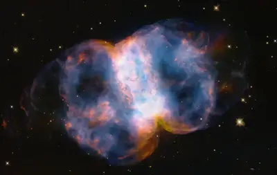 Hubble-Aufnahme des Kleinen Hantelnebels M76 mit zwei glühenden Gaslappen und einem zentralen ringförmigen Balken